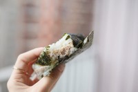 un onigiri thon mayonnaise tenu en main